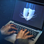 Persona usando portátil con icono de escudo digital que representa ciberseguridad y protección de datos